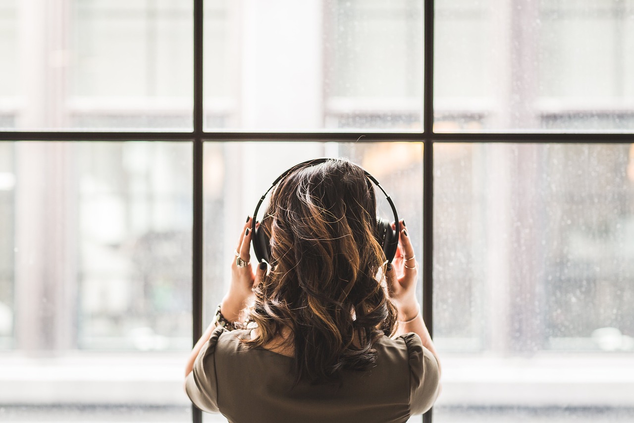 ヘッドホンで音楽を聴いている女性の後ろ姿