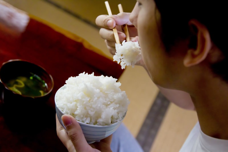 お茶碗に山盛りのごはんを食べる男性