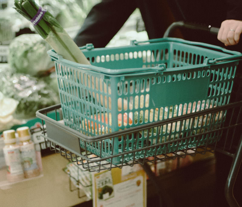 スーパーでカートを押しながら野菜を買っている写真